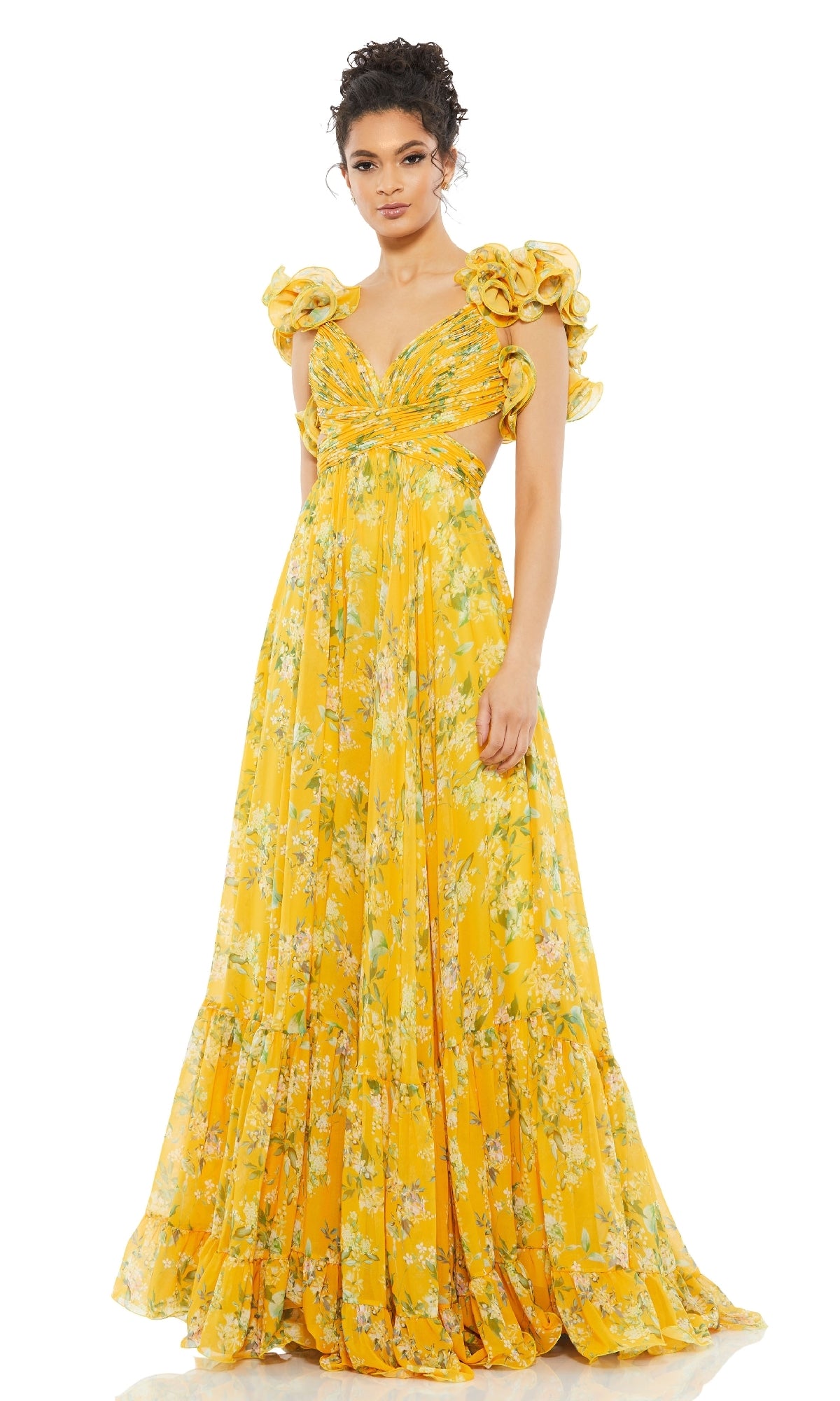 A woman models the Mac Duggal 67803 Ruffled Long Print Formal Dress, featuring yellow floral patterns and ruffled shoulders, standing against a plain white background.